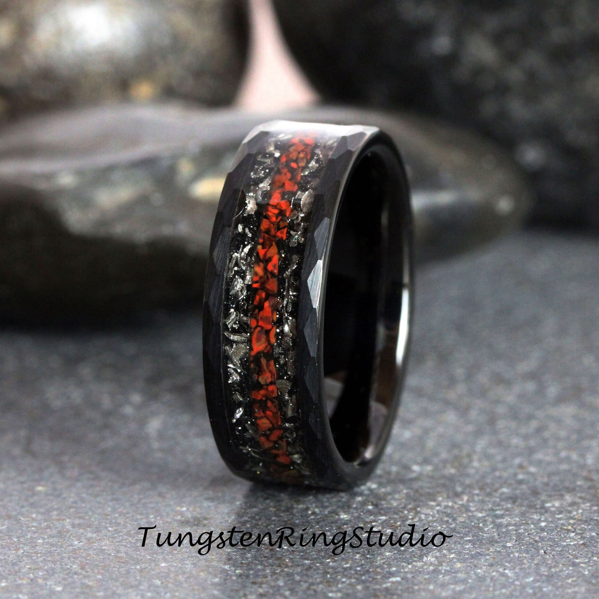May include: Black tungsten carbide ring with a hammered finish and a red and silver inlay. Tungsten Ring Studio.