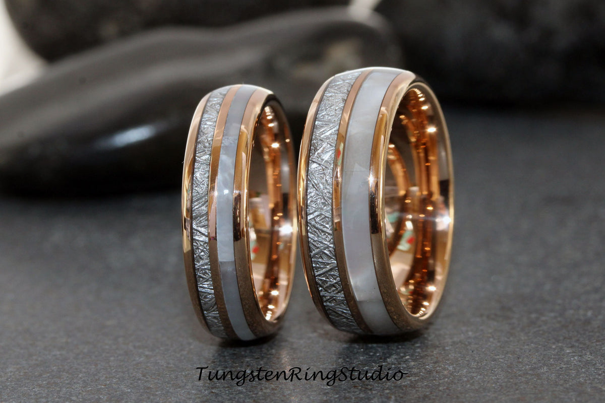 May include: Two matching tungsten carbide wedding bands with a rose gold inlay and a white mother of pearl inlay. The bands have a hammered finish.
