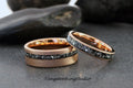 May include: Two rose gold wedding rings. The wider ring has a textured finish and a band of dark gray stones. The thinner ring has a similar design. The text "TungstenRingStudio" is visible.