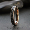 May include: A rose gold tungsten carbide ring with a black diamond inlay. The ring is a simple band with a smooth finish.