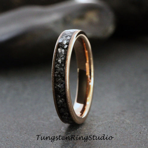 May include: A rose gold tungsten carbide ring with a black diamond inlay. The ring is a simple band with a smooth finish.