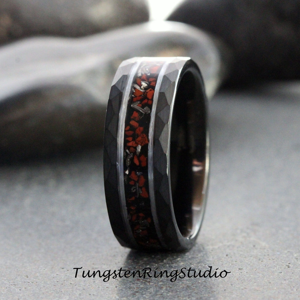 May include: A black tungsten carbide ring with a hammered finish and a red and silver inlay. The ring is approximately 8mm wide.