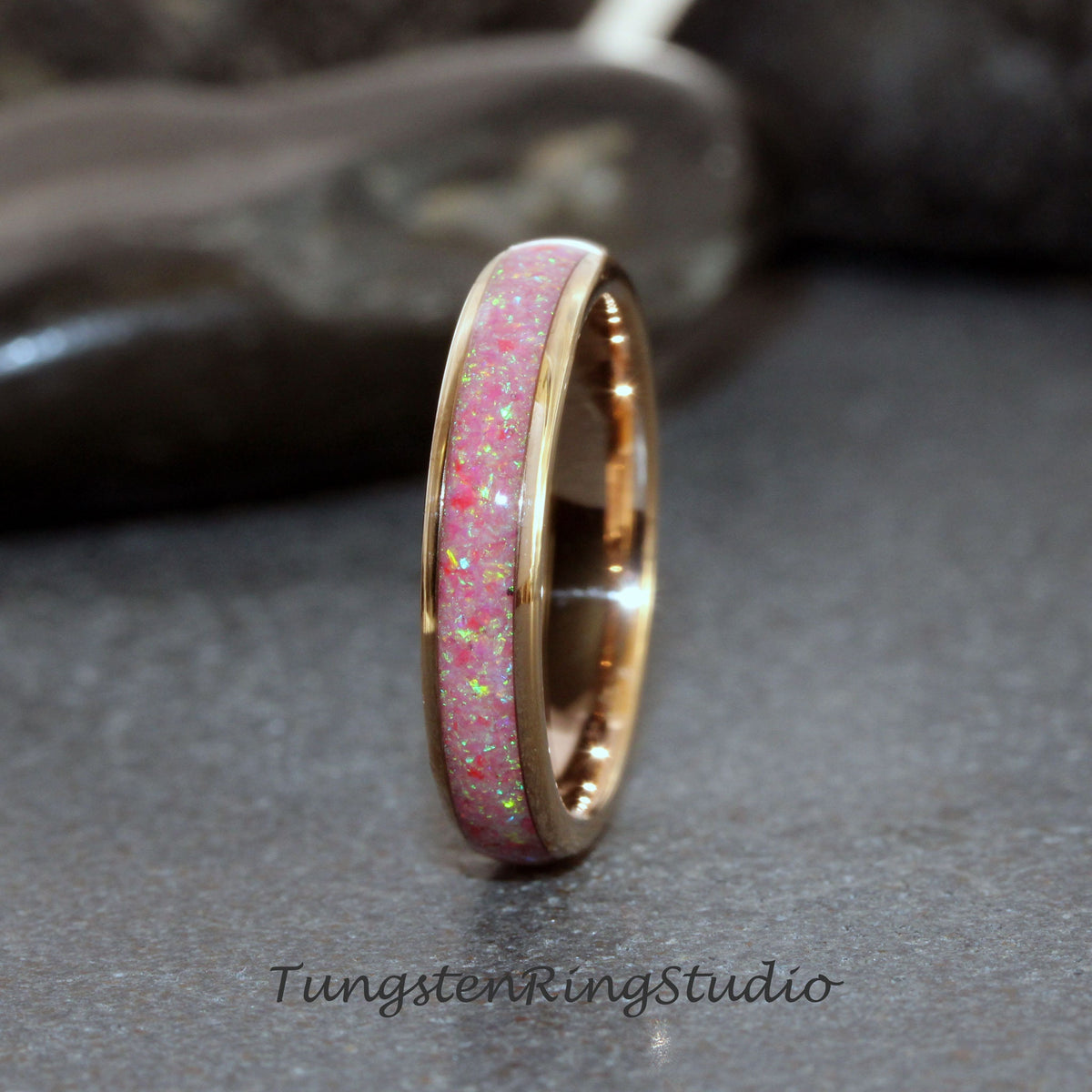 May include: A thin rose gold tungsten carbide ring with a pink opal inlay. The ring is polished and has a smooth finish.