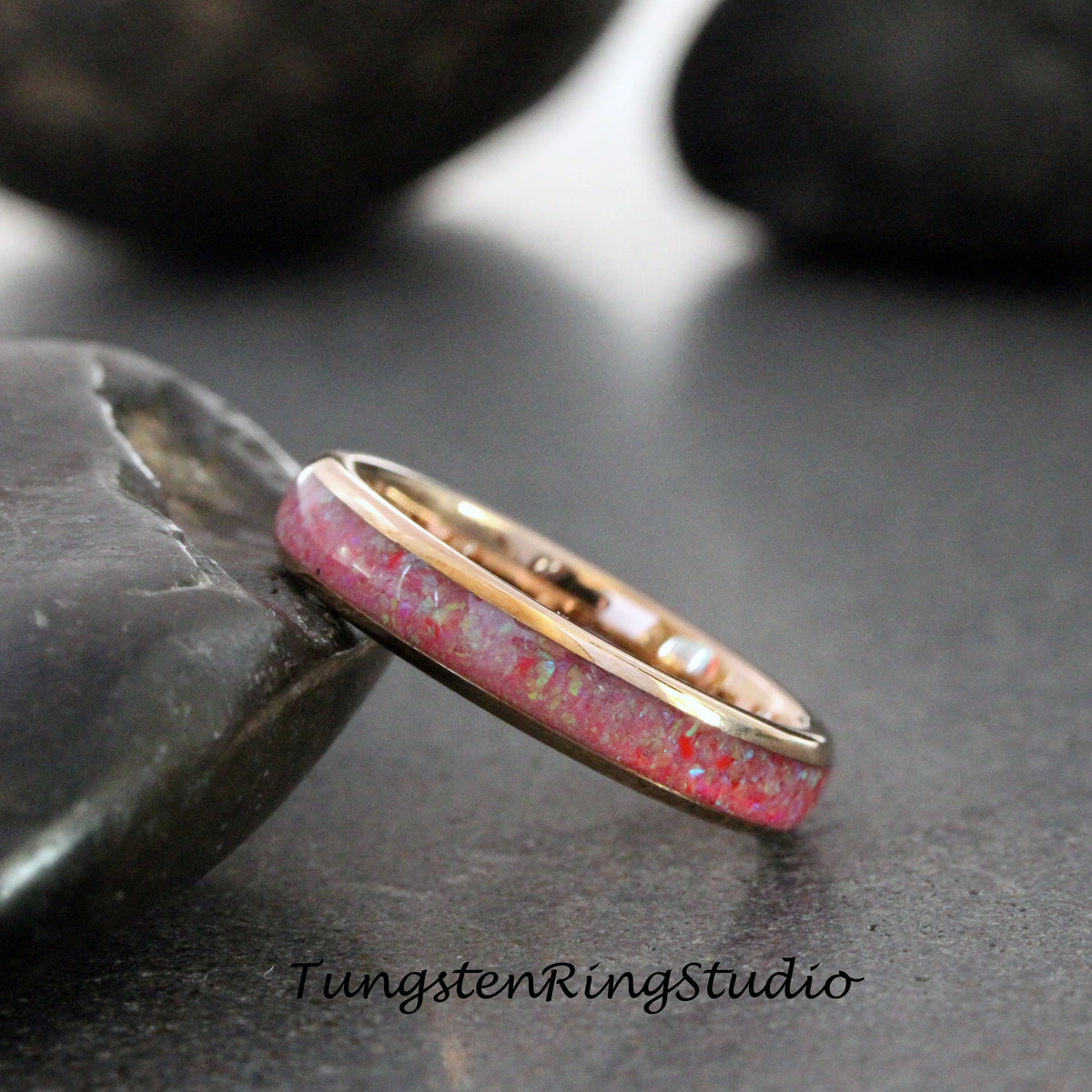 May include: A rose gold tungsten carbide ring with a pink and white opal inlay.