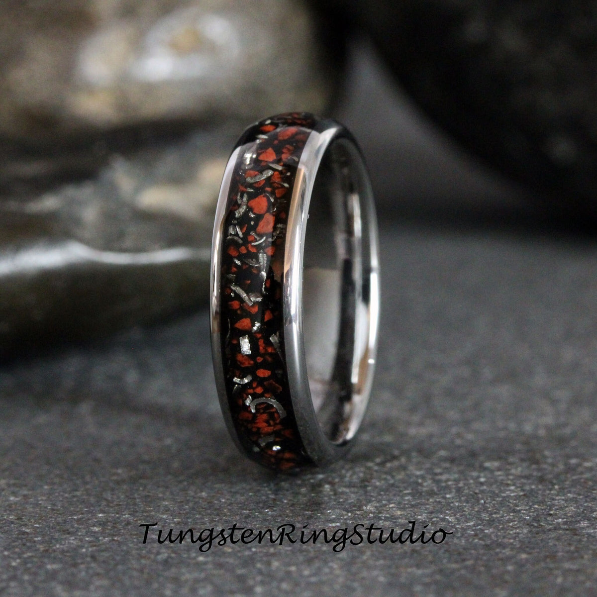 May include: A silver tungsten ring with a black and red inlay. The inlay has a speckled pattern of red and silver.
