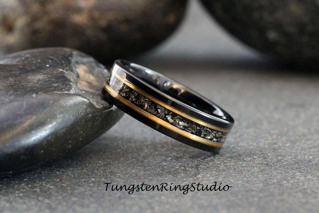 May include: Black tungsten carbide ring with a gold inlay and a black meteorite inlay. TungstenRingStudio.