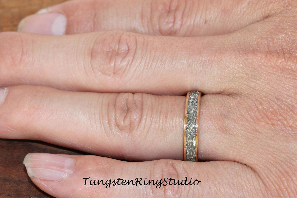 May include: A close-up of a silver tungsten ring with a rose gold band and a textured surface. The ring is worn on a person's finger.
