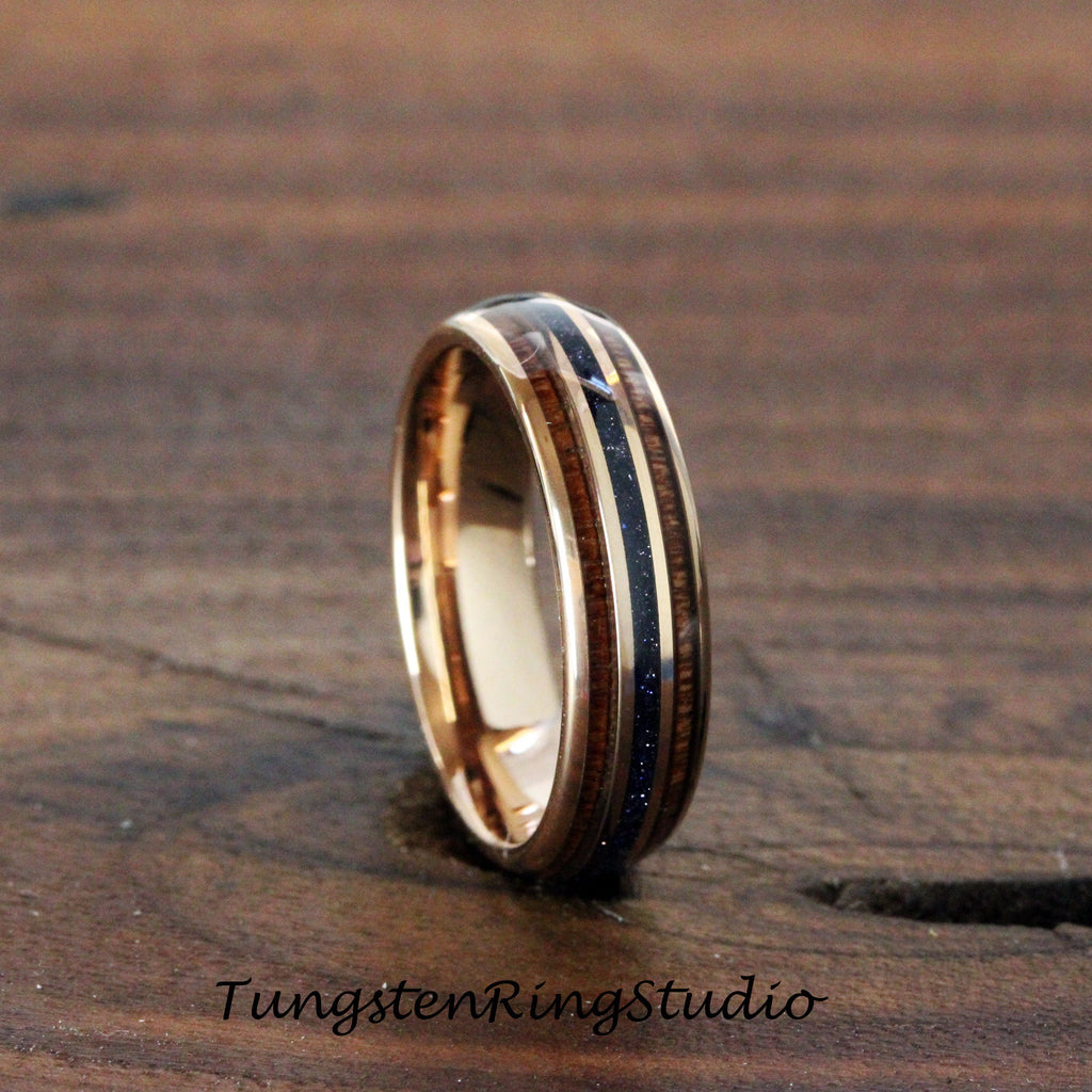 May include: A rose gold tungsten carbide ring with two bands of dark wood and a thin band of blue stone inlay.