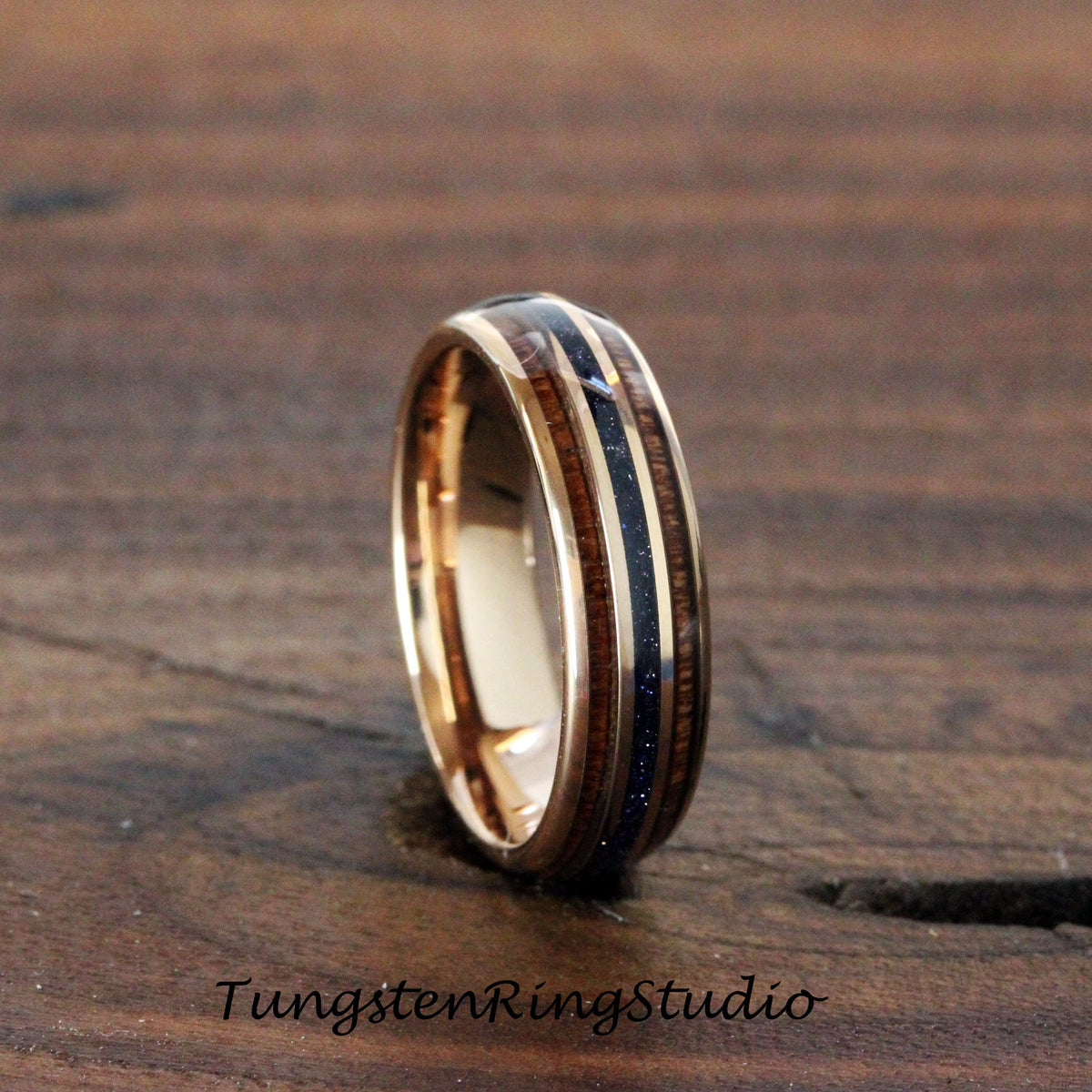 May include: A rose gold tungsten carbide ring with two bands of dark wood and a thin band of blue stone inlay.