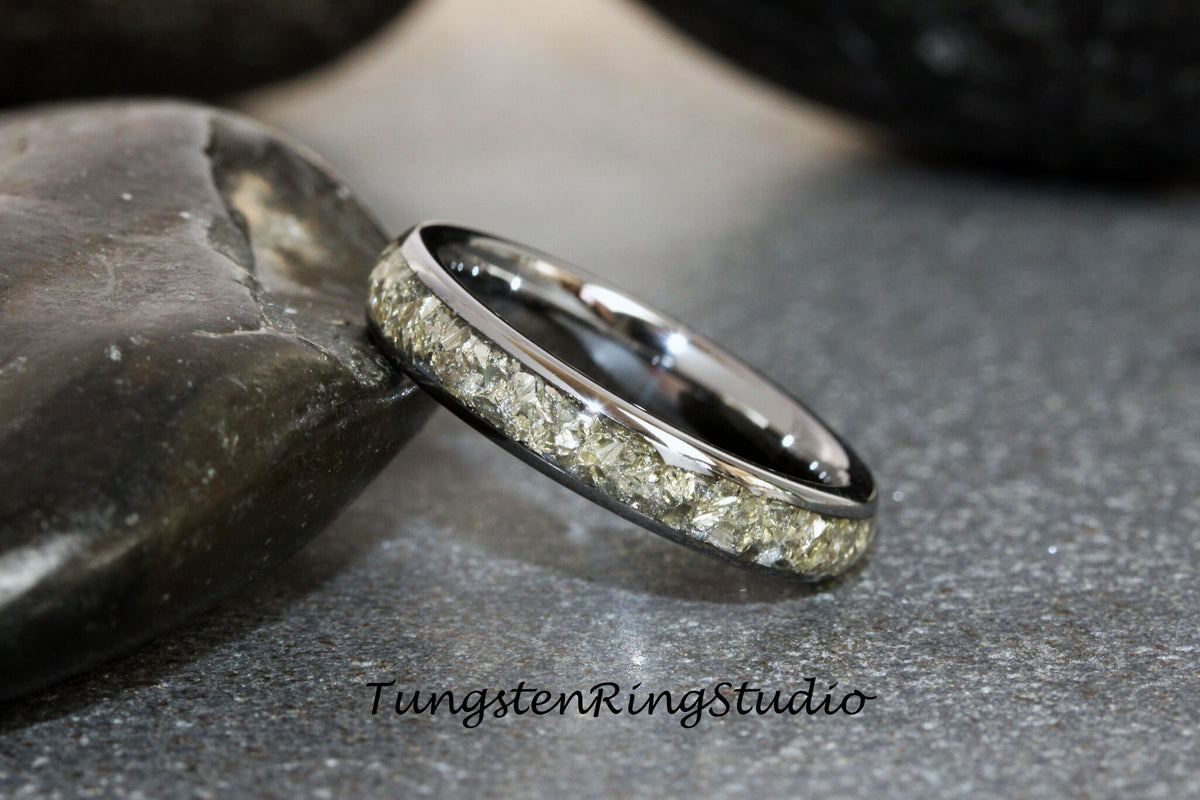 May include: A silver tungsten ring with a band of light green, sparkly stones.
