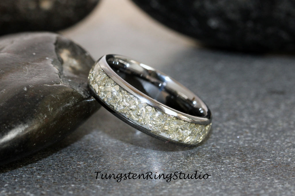 May include: A silver tungsten ring with a band of embedded light gray particles. The ring is on a gray surface.