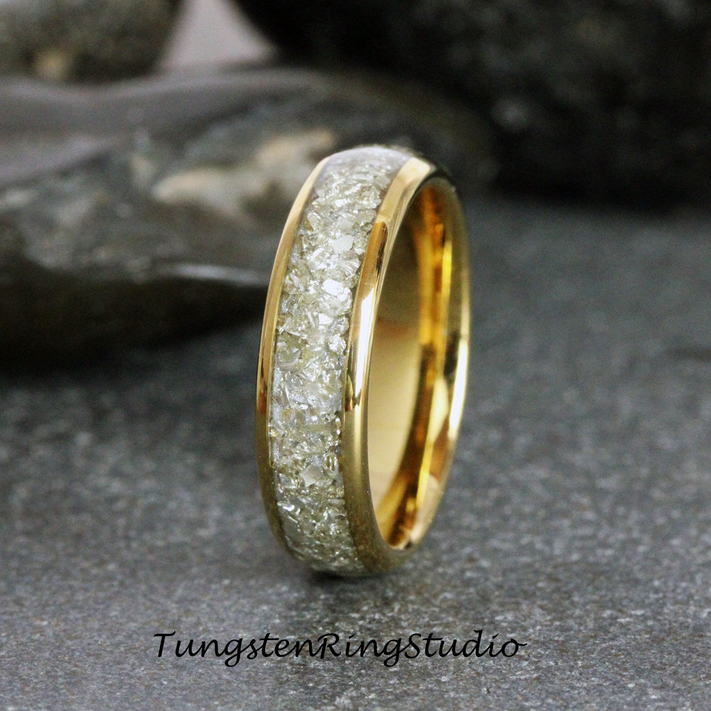 May include: A gold tungsten carbide ring with a band of crushed diamonds. The ring is a simple design with a polished finish.