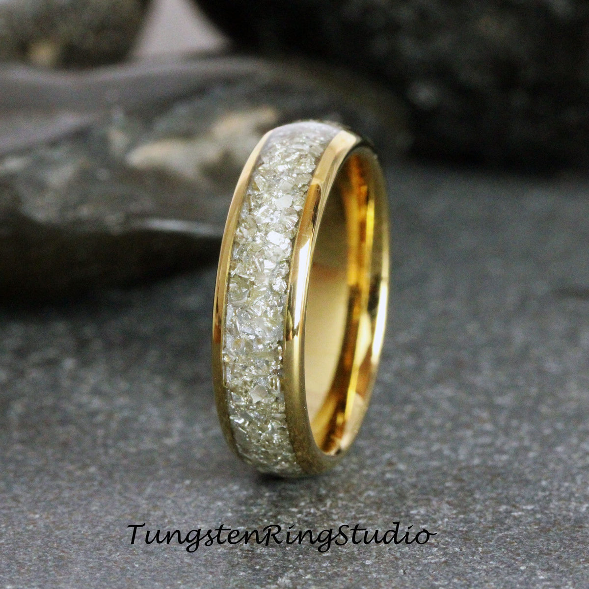May include: A gold tungsten carbide ring with a band of crushed diamonds. The ring is a simple design with a polished finish.
