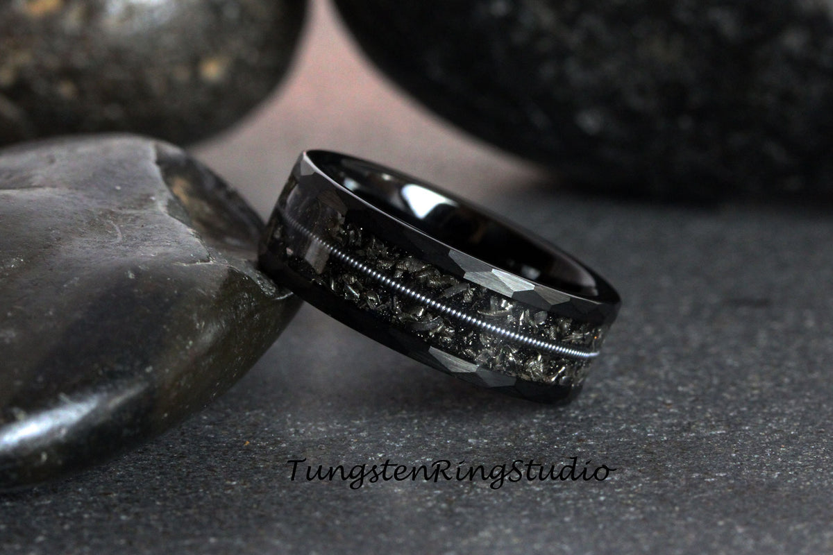 May include: Black tungsten carbide ring with a hammered finish and a silver inlay. The ring is on a gray background.
