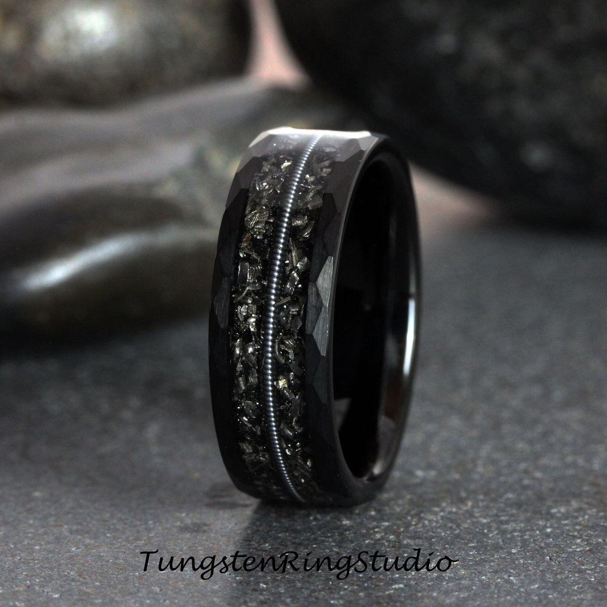 May include: Black tungsten carbide ring with a hammered finish and a silver inlay. The ring has a textured surface and a polished edge.