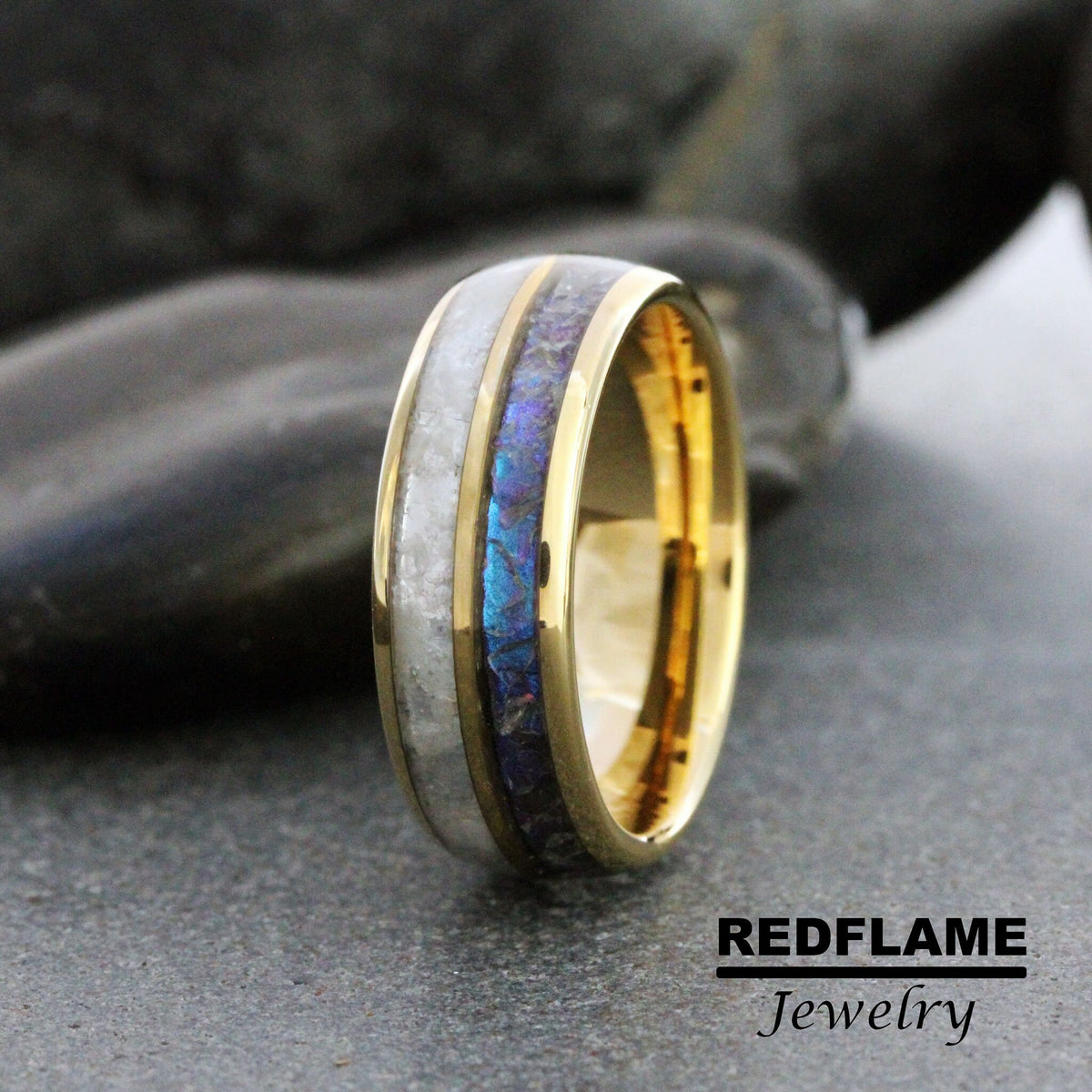 May include: A gold band with a white and blue inlay. The band is made of metal and has a polished finish. The inlay is made of a material that appears to be wood or stone. The band is a wedding ring.
