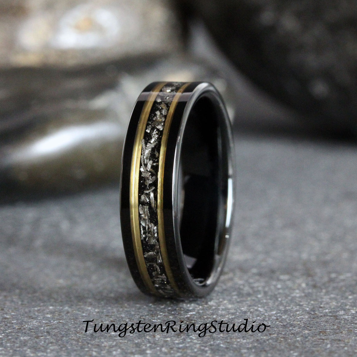 May include: A black tungsten carbide ring with a gold inlay and a silver meteorite inlay. The ring is polished and has a beveled edge.