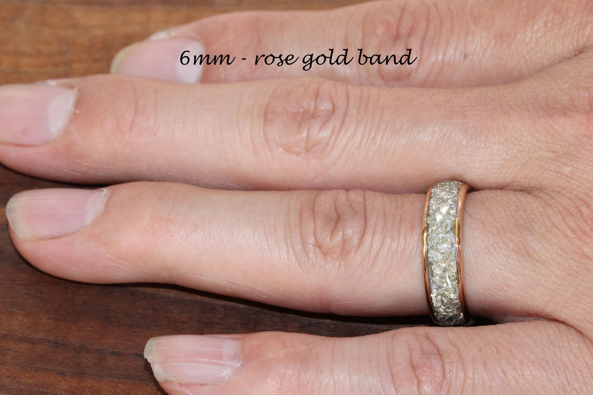 May include: A rose gold band ring with a row of small diamonds set in the band. The ring is 6mm wide and is shown on a finger.