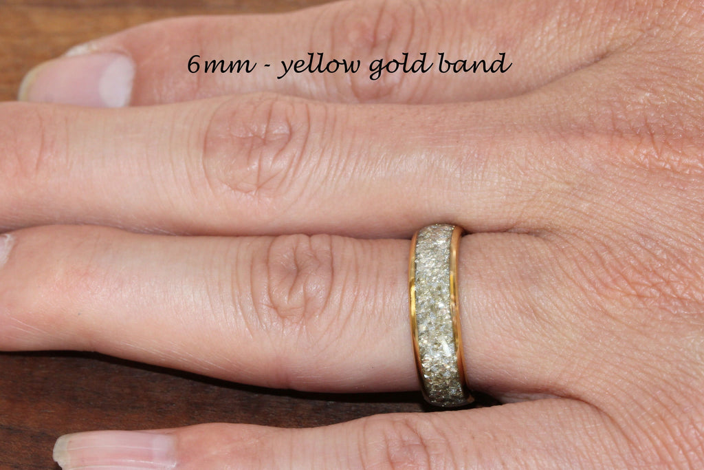May include: A 6mm yellow gold band with a row of small, clear stones around the edge.