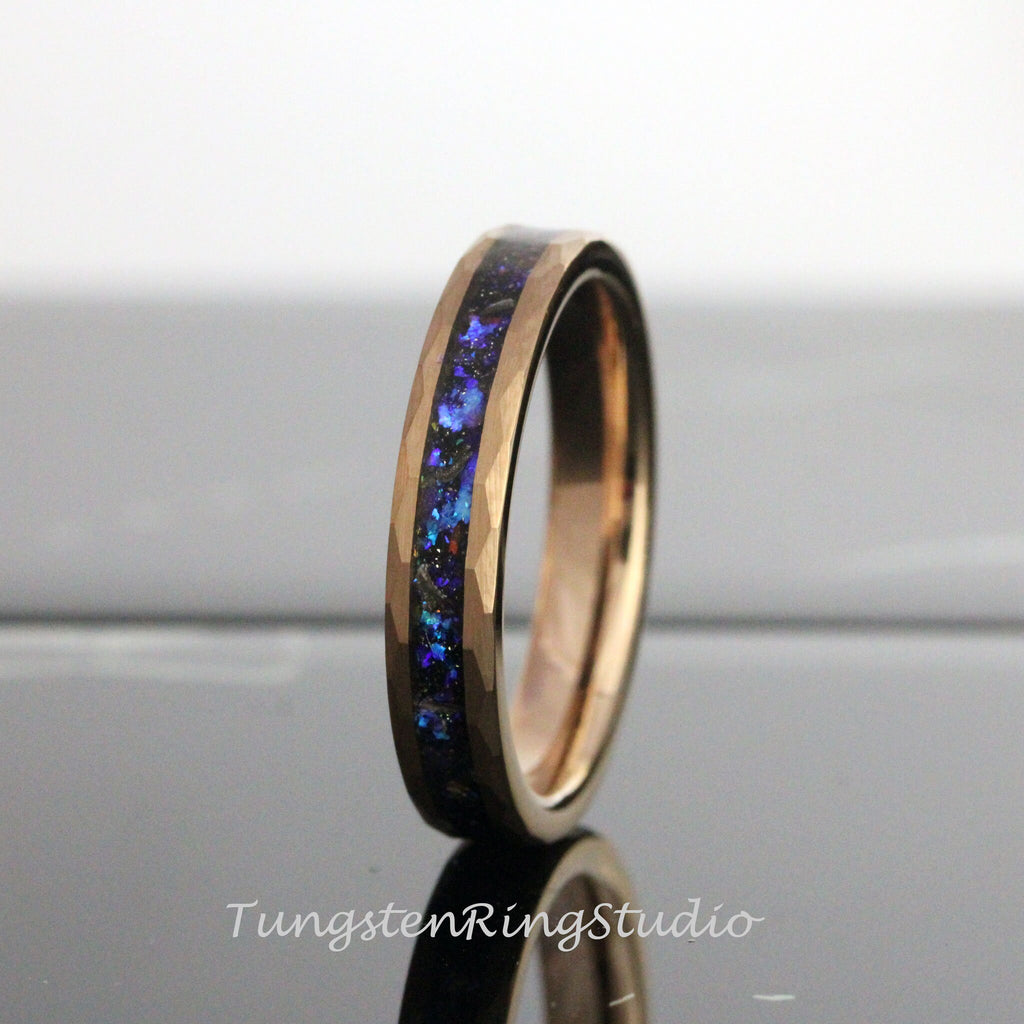 May include: A rose gold tungsten carbide ring with a blue and black inlay. The ring has a hammered finish.
