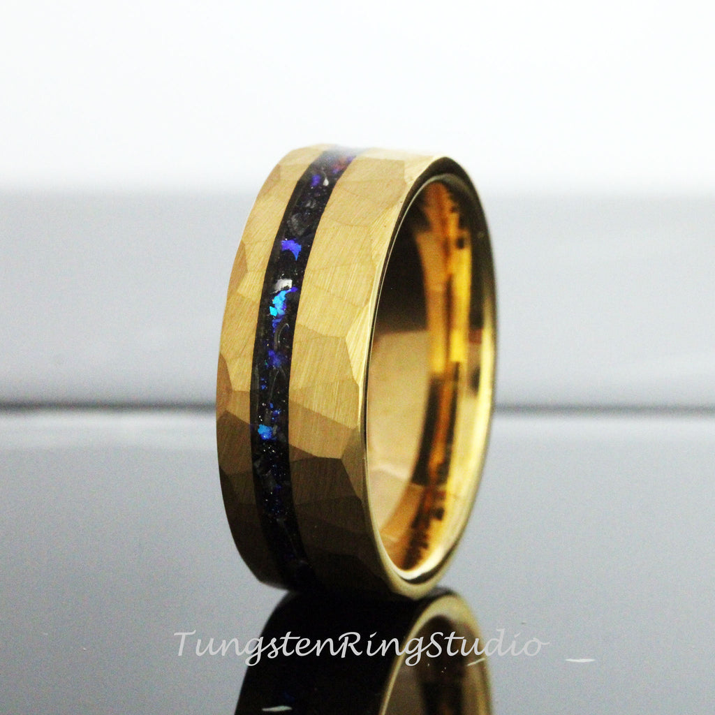 May include: A gold tungsten carbide ring with a hammered finish and a black inlay with blue iridescent accents.