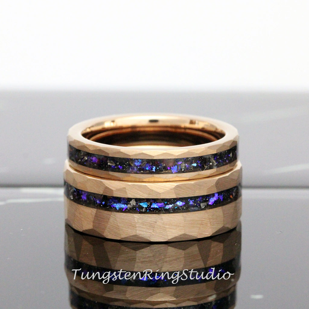 May include: Two gold tungsten carbide rings with a hammered finish and a thin band of iridescent blue and black inlay.
