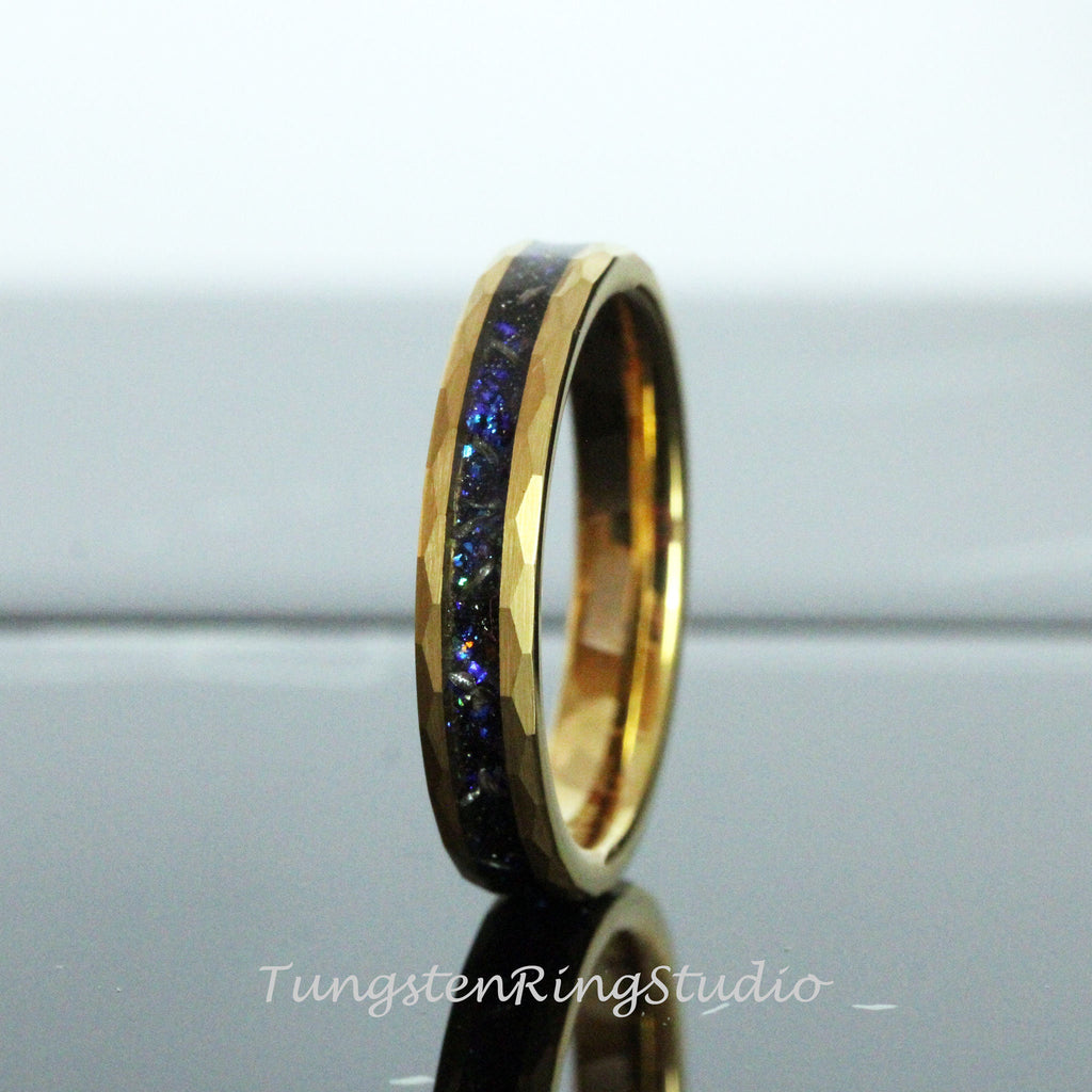 May include: A gold tungsten carbide ring with a blue and black inlay. The ring has a hammered finish.