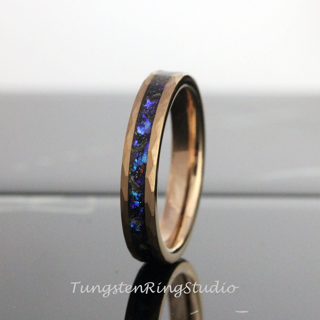 May include: A rose gold tungsten carbide ring with a blue and black inlay. The ring has a hammered finish.