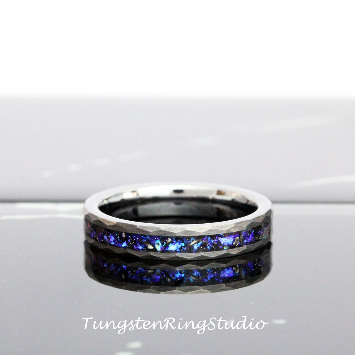 May include: A silver tungsten ring with a blue and black inlay. The ring has a hammered finish and a beveled edge.