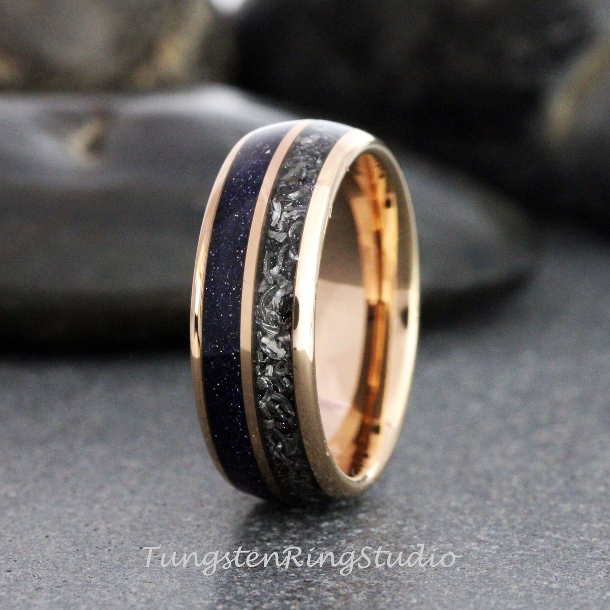 May include: A rose gold tungsten carbide ring with a black and gray inlay. The ring has a polished finish and a comfortable fit.