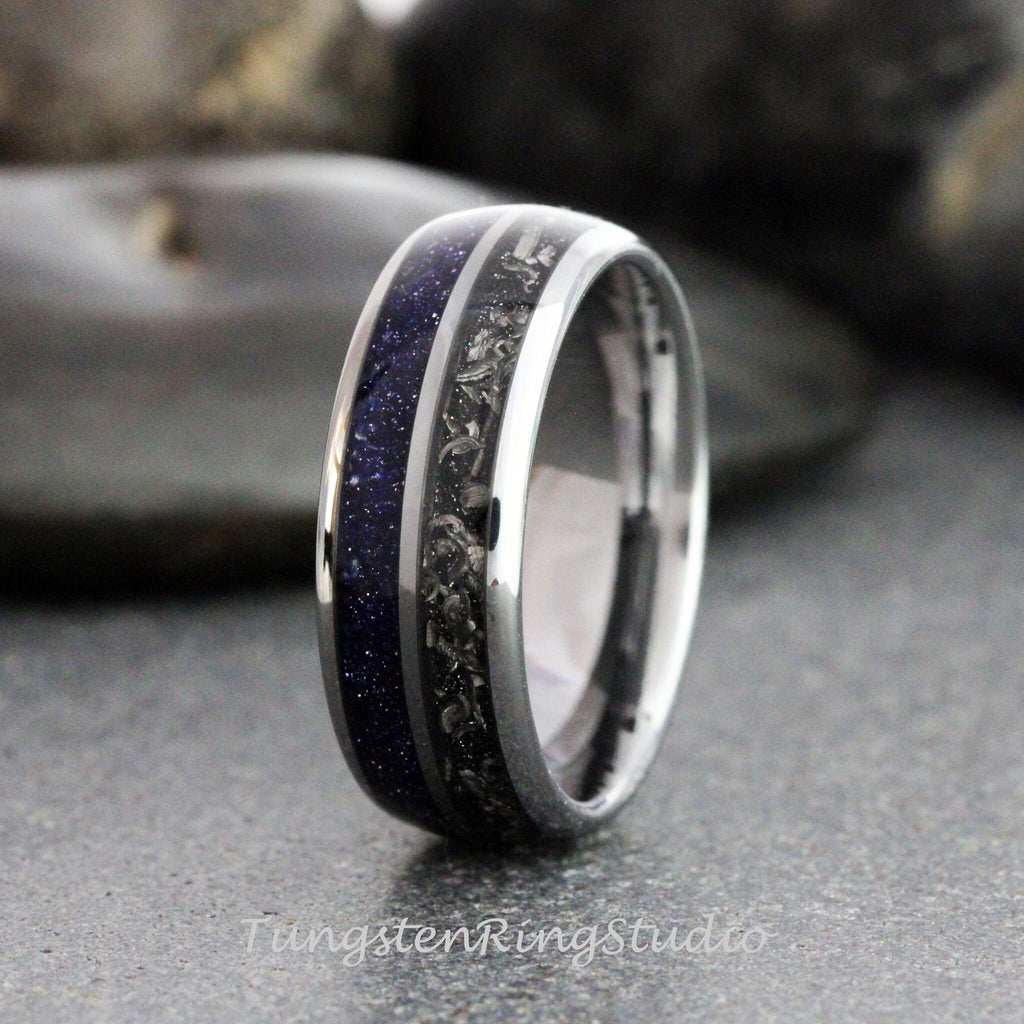 May include: A close-up of a silver ring with a dark blue, speckled inlay and a dark gray, textured inlay. The ring has a polished, metallic finish. The text "TungstenRingStudio" is visible at the bottom.