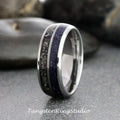May include: A close-up of a silver ring with a dark blue, speckled center band and a black, textured band. The ring has a polished, metallic finish. The text "TungstenRingStudio" is at the bottom.
