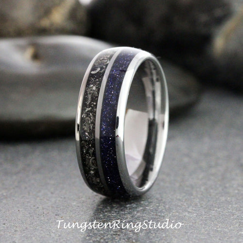May include: A close-up of a silver ring with a dark blue, speckled center band and a black, textured band. The ring has a polished, metallic finish. The text "TungstenRingStudio" is at the bottom.