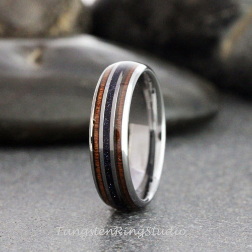 May include: A silver tungsten ring with two brown wood inlays and a black and silver inlay. The ring is polished and has a smooth finish.