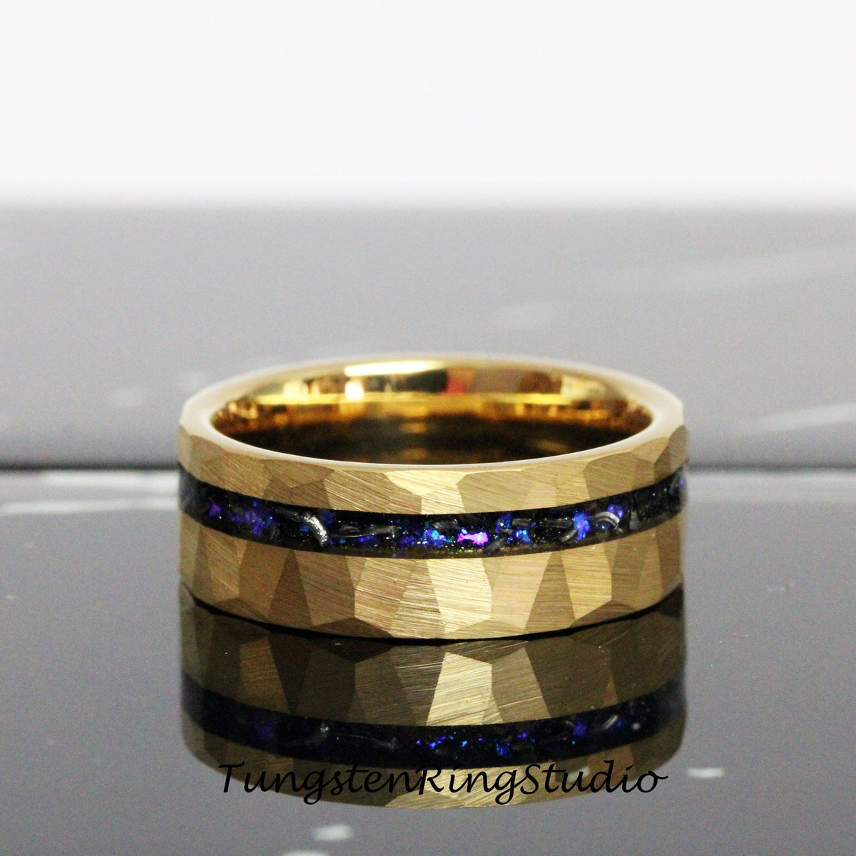 May include: A gold tungsten carbide ring with a hammered finish and a black inlay with blue and purple glitter.