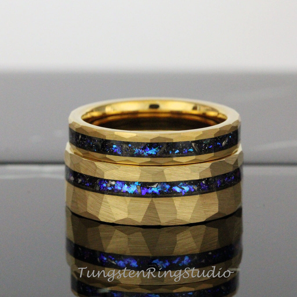May include: Two gold tungsten carbide rings with a hammered finish and a blue and black inlay. The rings are stacked on top of each other.