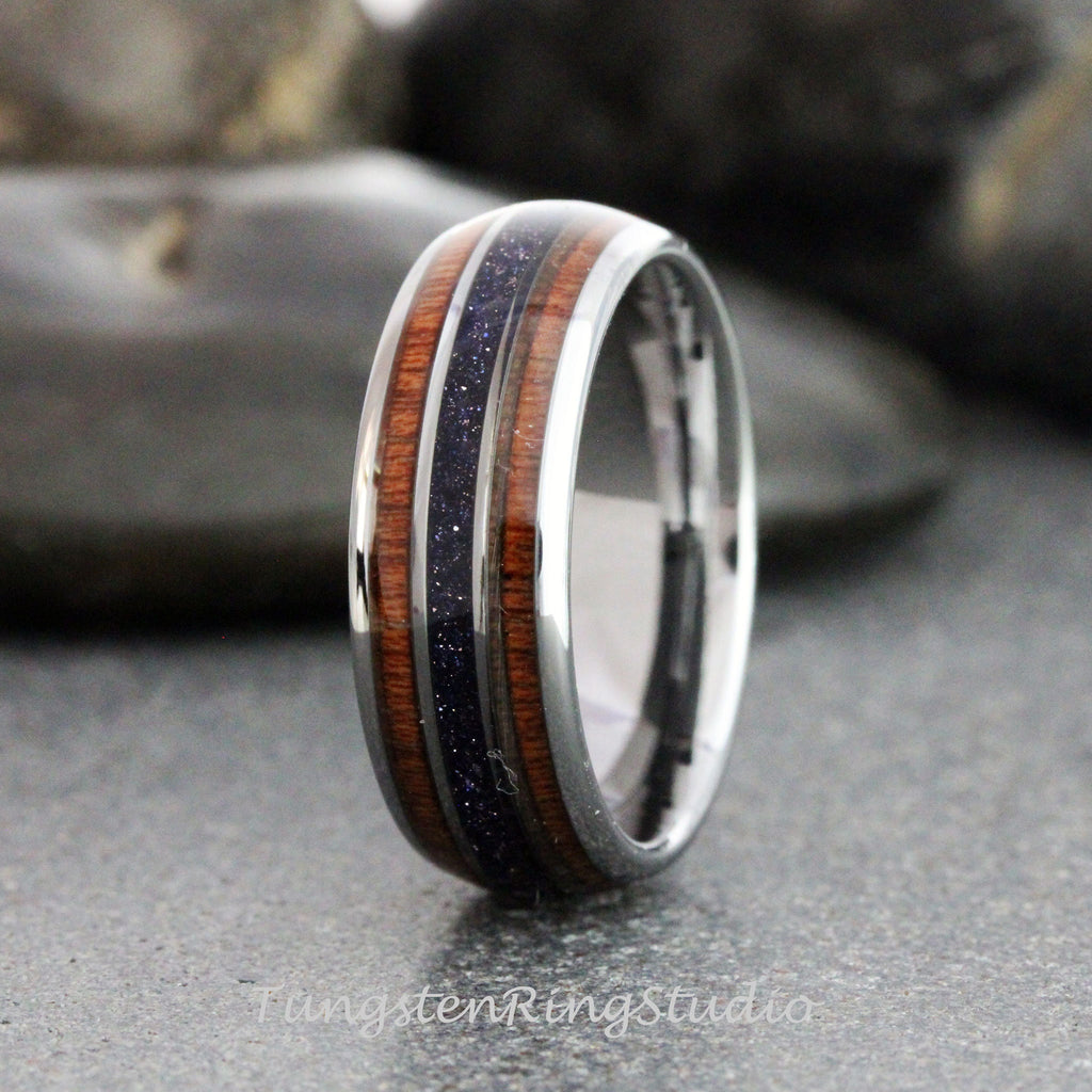 May include: A silver tungsten ring with a brown wood inlay and a thin band of purple glitter.