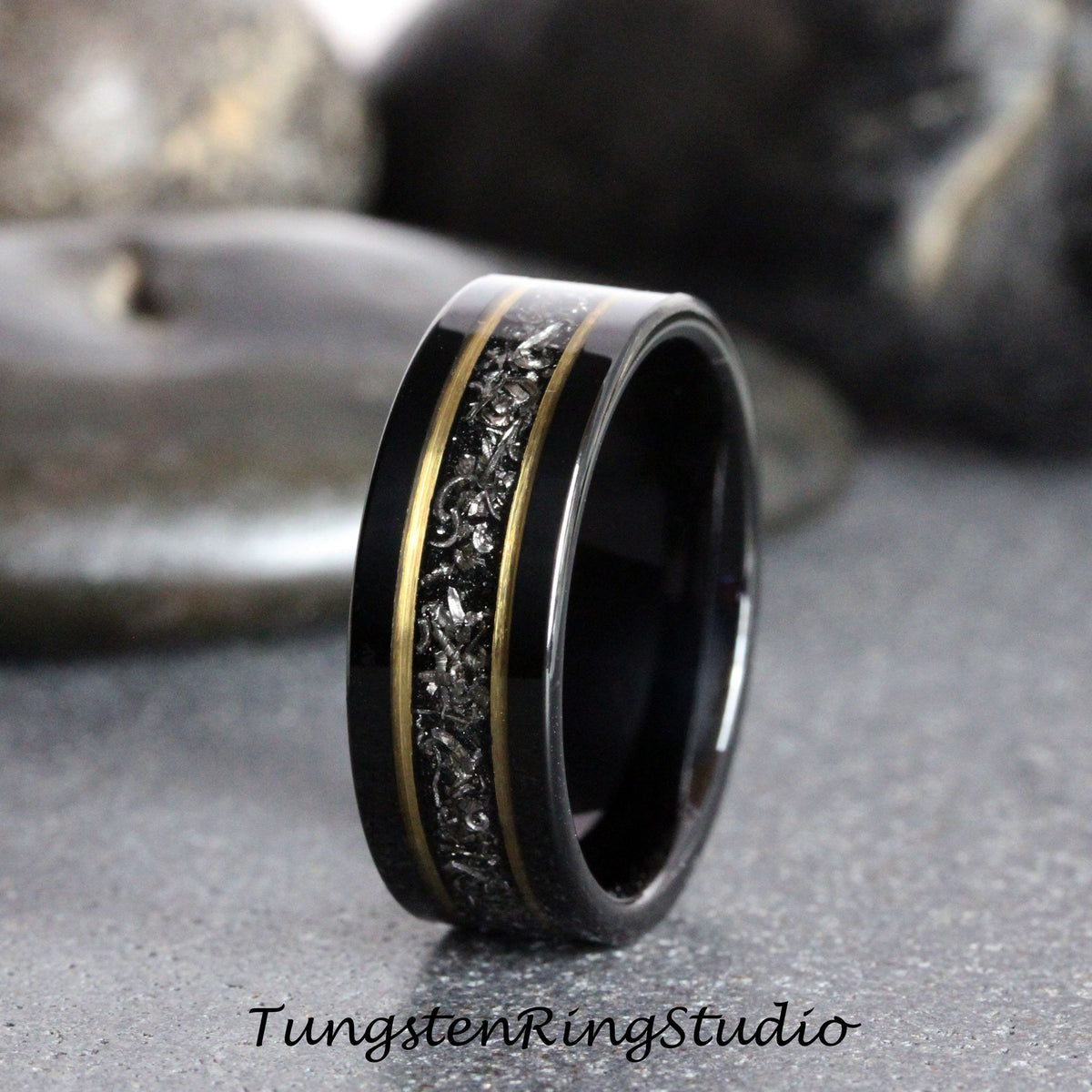 May include: Black tungsten carbide ring with a gold inlay and a black and silver patterned design.