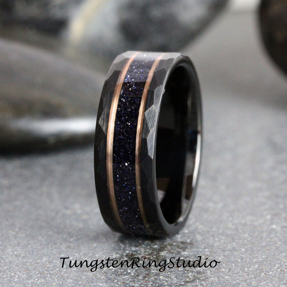 May include: A black tungsten ring with a hammered finish and a thin band of rose gold with blue glitter embedded in it.