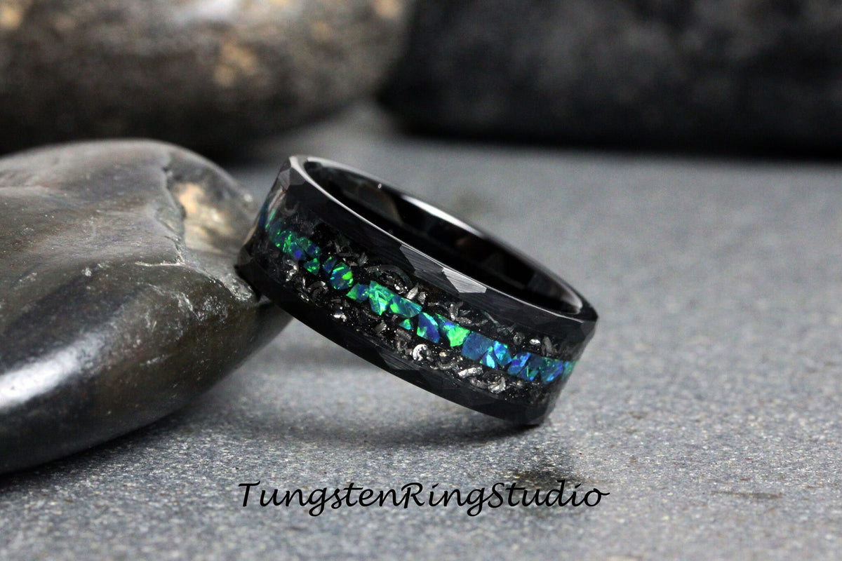 May include: Black tungsten ring with a band of green and blue opal inlay. The ring has a hammered finish and is set against a gray background.