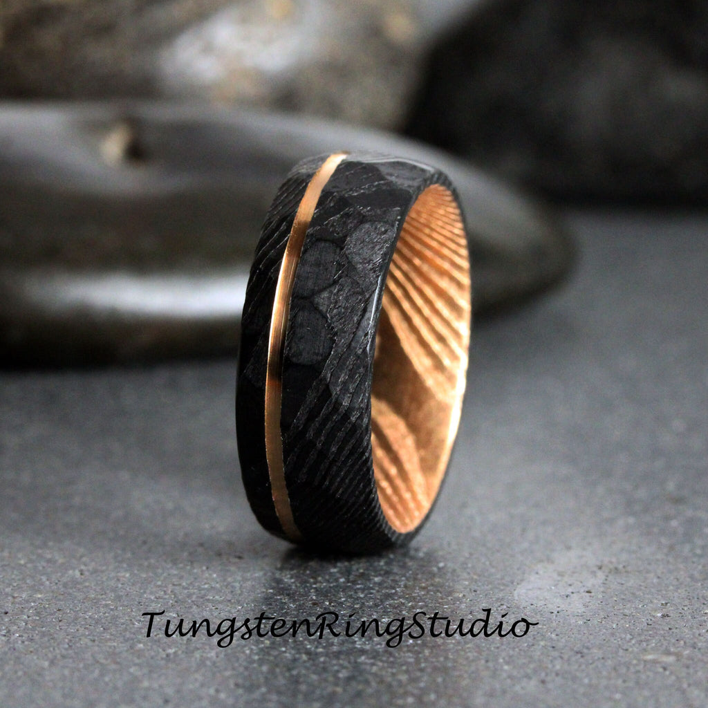 May include: A black tungsten carbide ring with a gold inlay and a wood inlay. The ring has a textured finish.