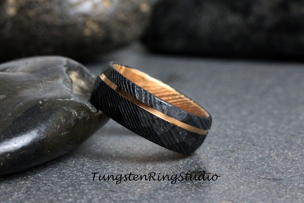 May include: A black tungsten ring with a gold inlay. The ring has a textured surface and is shown on a gray background.
