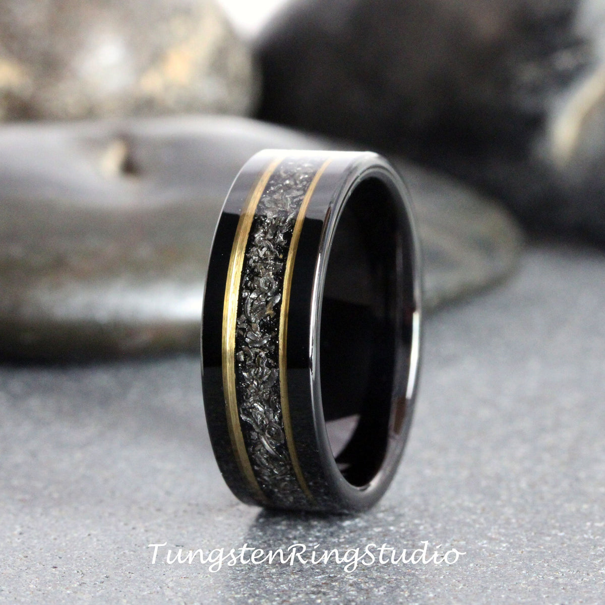 May include: Black tungsten carbide ring with a gold inlay and a black and silver meteorite pattern.