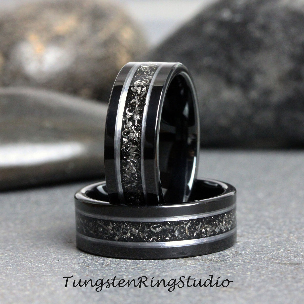 May include: Two black tungsten carbide rings with a silver inlay design. The rings are stacked on top of each other.