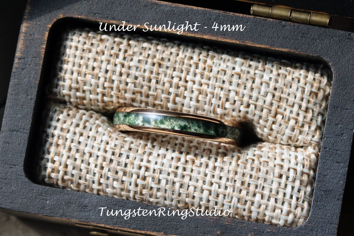 May include: A green and gold tungsten ring with a green stone inlay, in a small wooden box with a beige fabric lining. The text "Under Sunlight - 4mm" is visible above the ring. The text "TungstenRingStudio" is visible below the ring.