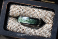 May include: A tungsten ring with a green agate inlay. The ring is 8mm wide and is displayed in a wooden box with a fabric lining. The text "under sunlight - 8mm" and "TungstenRingStudio" are visible in the image.