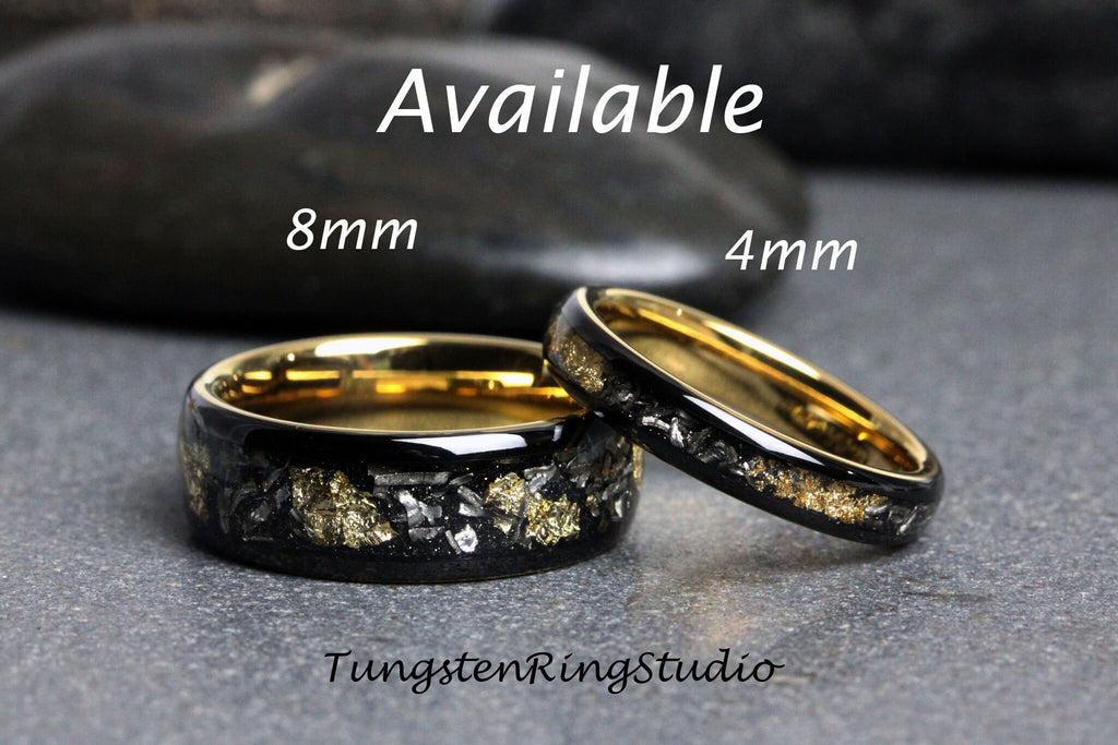 May include: Two tungsten carbide rings with a black finish and gold accents. The larger ring is 8mm wide and the smaller ring is 4mm wide. The rings have a unique design with black and gold flecks embedded in the surface. The rings are available in different sizes.