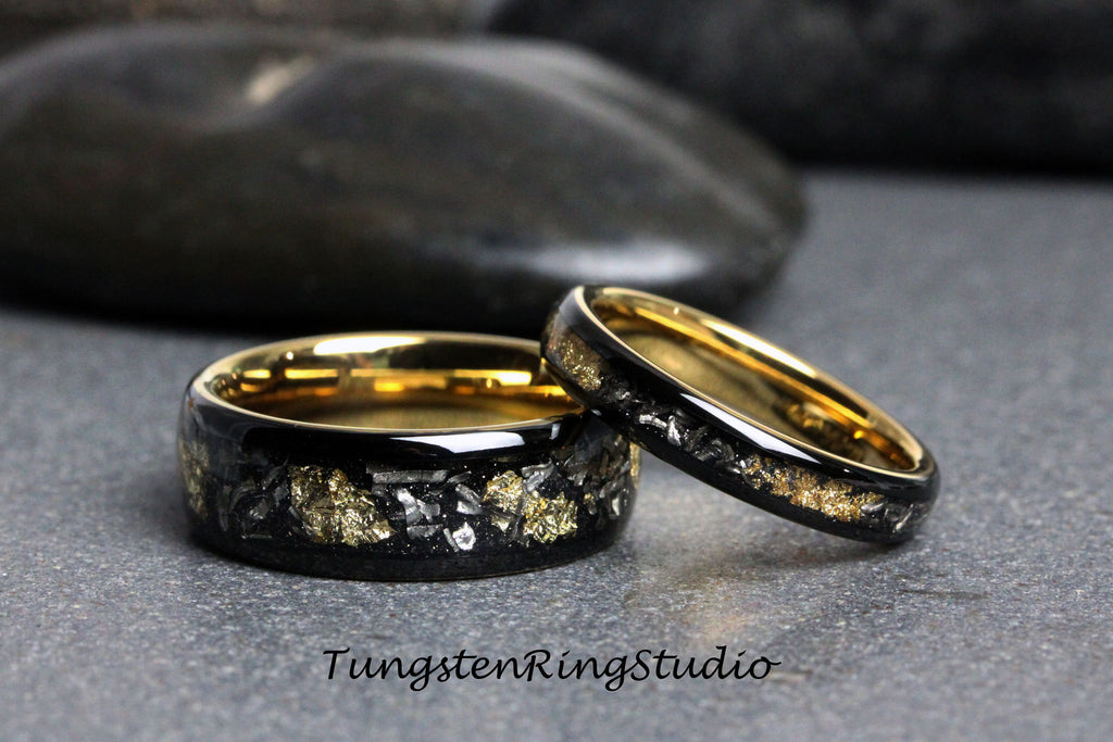 May include: Two black tungsten carbide rings with gold inlay. The rings have a hammered finish and are set against a gray background.