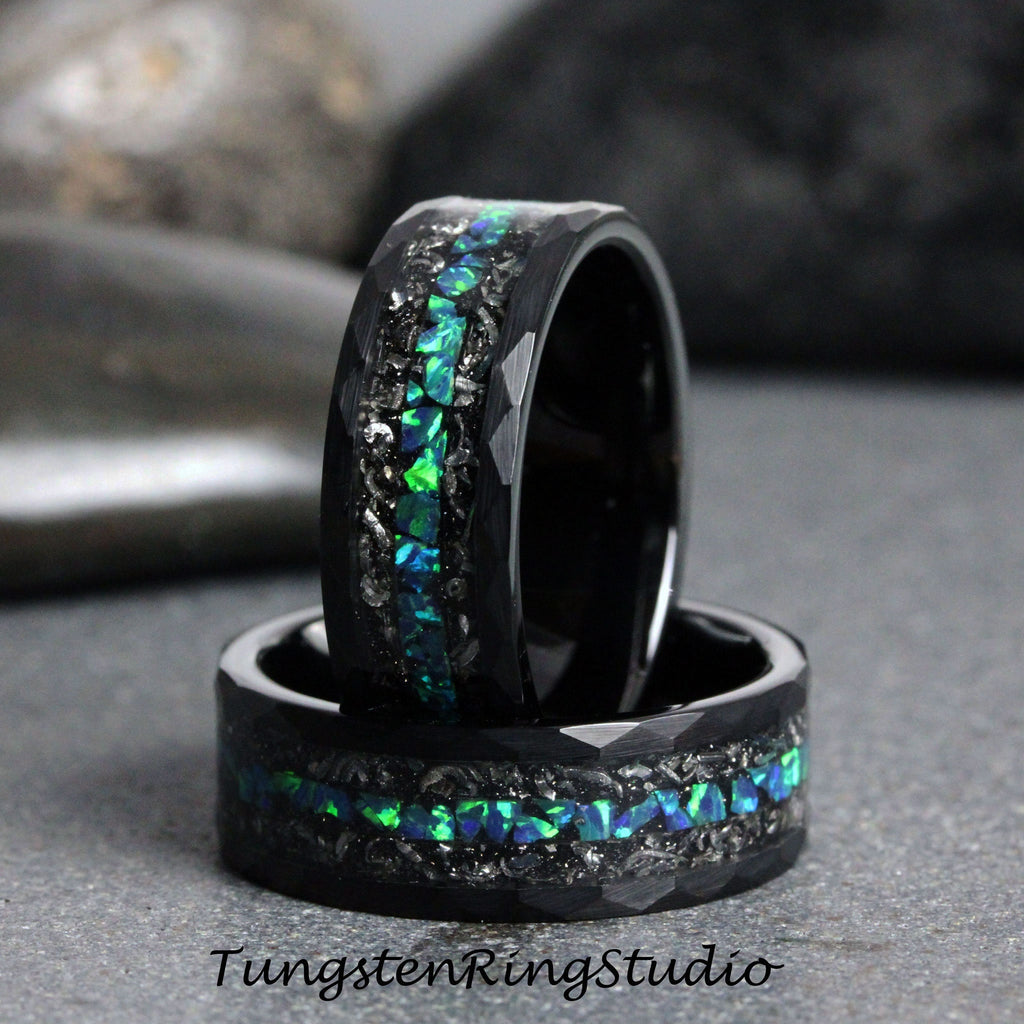May include: Two black tungsten carbide rings with a green and blue opal inlay. The rings have a hammered finish and are stacked on top of each other.