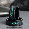 May include: Two black tungsten carbide rings with a green and blue opal inlay. The rings have a hammered finish and are stacked on top of each other.
